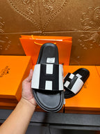 Hermes slide sandal close-up held, black sole with white strap and black insets