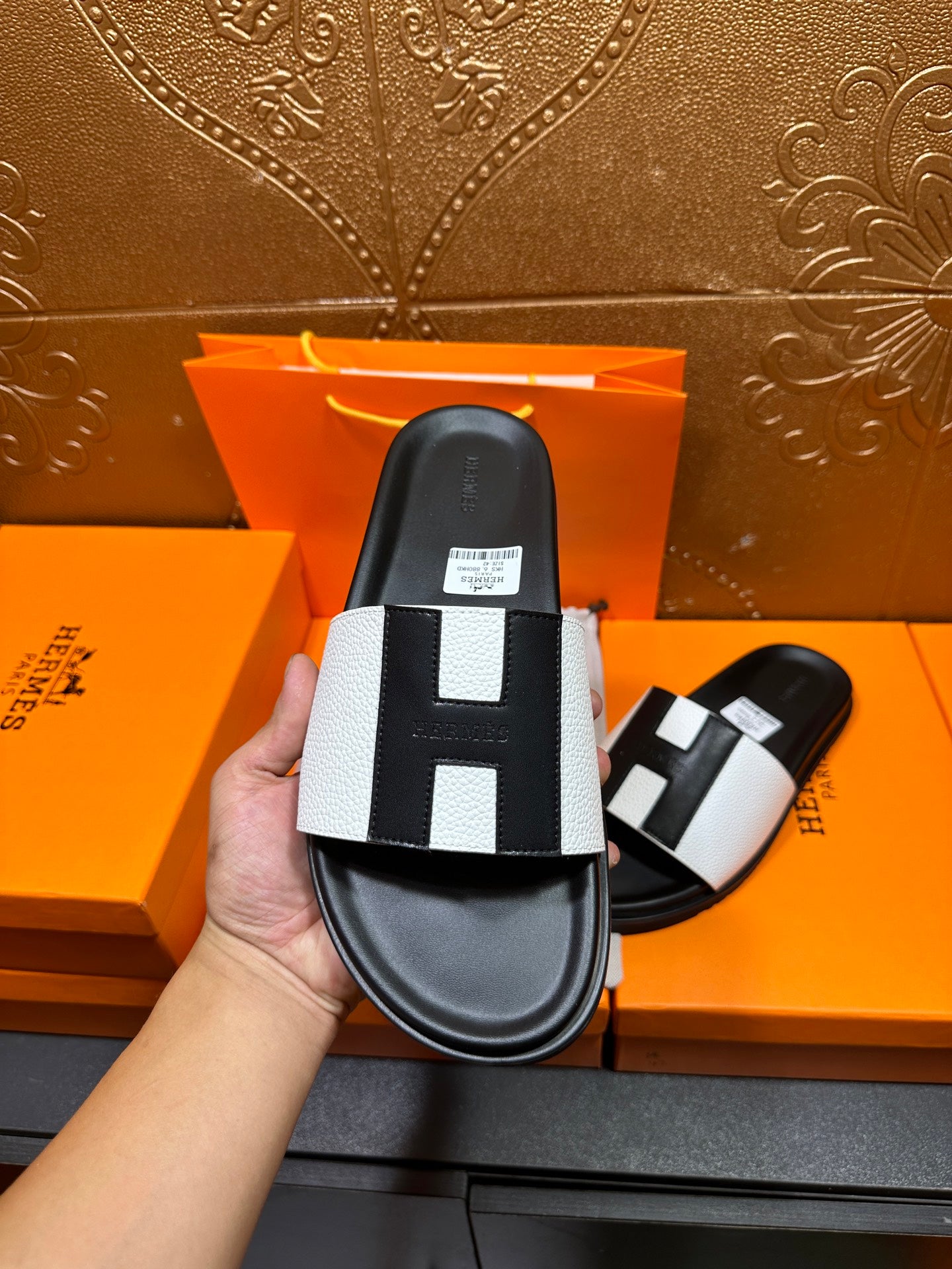 Hermes slide sandal close-up held, black sole with white strap and black insets