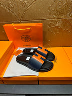Black slide sandals with orange H strap detail, open toe style