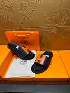 Two black slide sandals with orange H strap detail on a cloth insert
