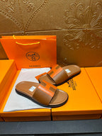 Tan and orange H-strap sandals in open orange gift box with tissue.