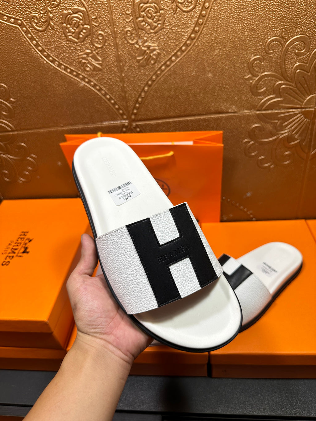 Hermes slide sandal held up: white sole with black H-style strap