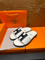 Hermes slide sandals pair, white upper with black H-style strap over footbed