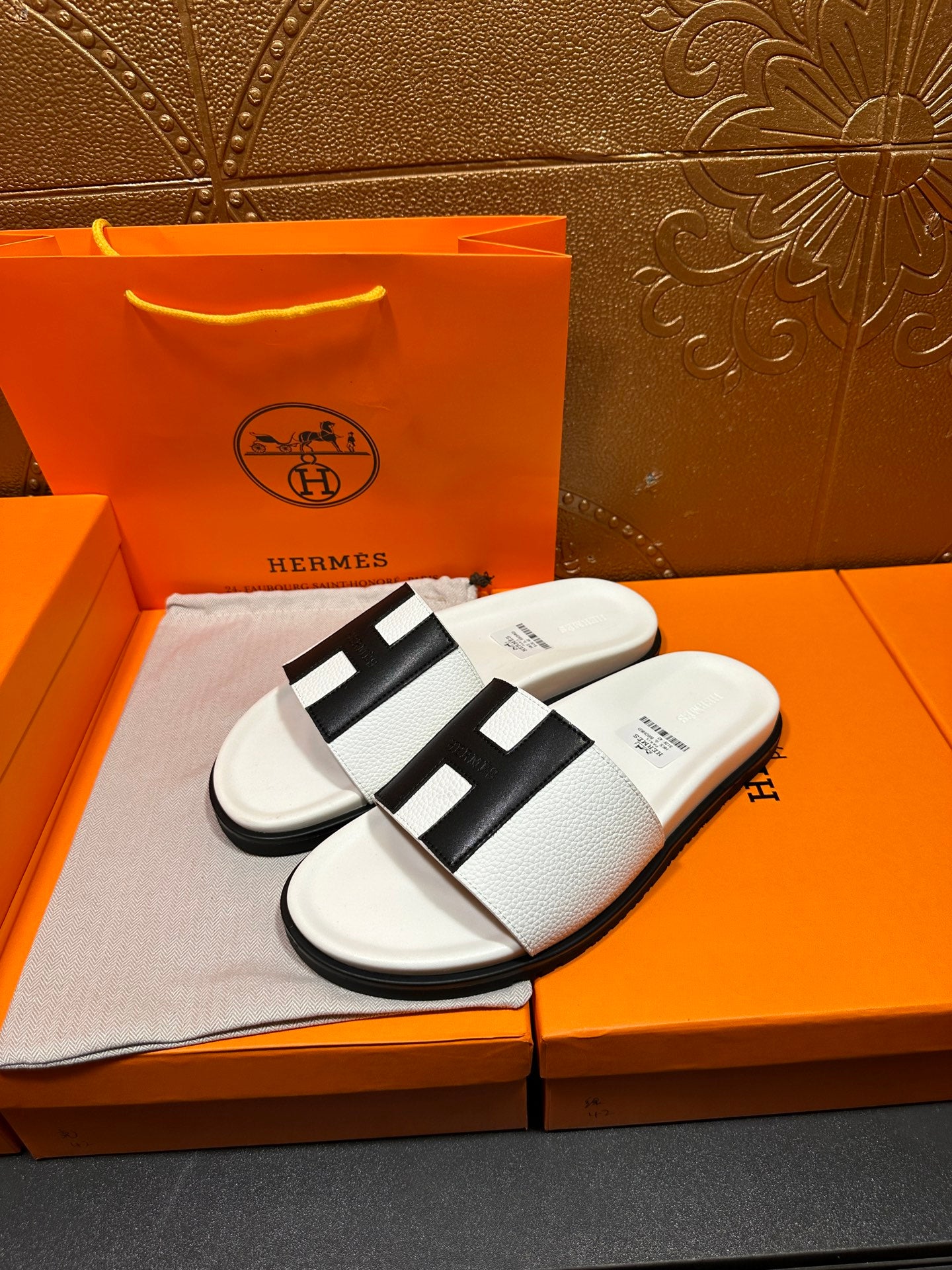 Hermes slide sandals pair, white upper with black H-style strap over footbed