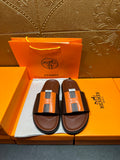 Leather sandals with brown straps and orange H-style buckle detail, pair on box