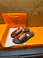 Leather sandals with orange H strap detail and dark footbed, pair on display box