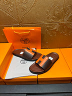 Leather sandals with orange H strap detail, dark footbed, pair resting on box