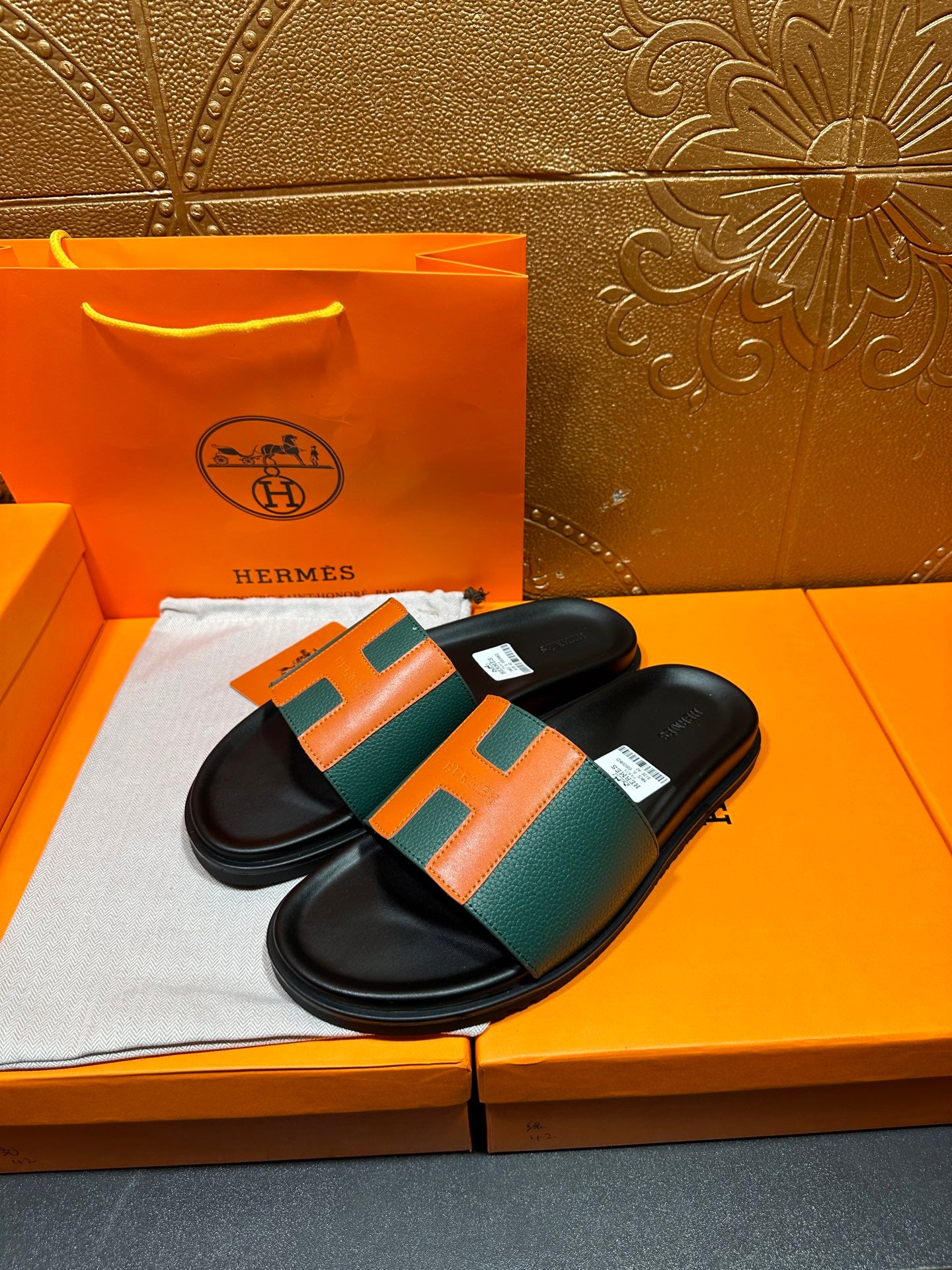 Hermes slide sandals, black slides with green and orange H over straps.