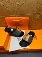 Hermes slide sandals pair on box, black soles with green and orange H straps.