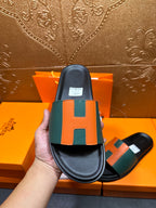 Hermes slide sandal, rear view of black sole and green-orange H strap.