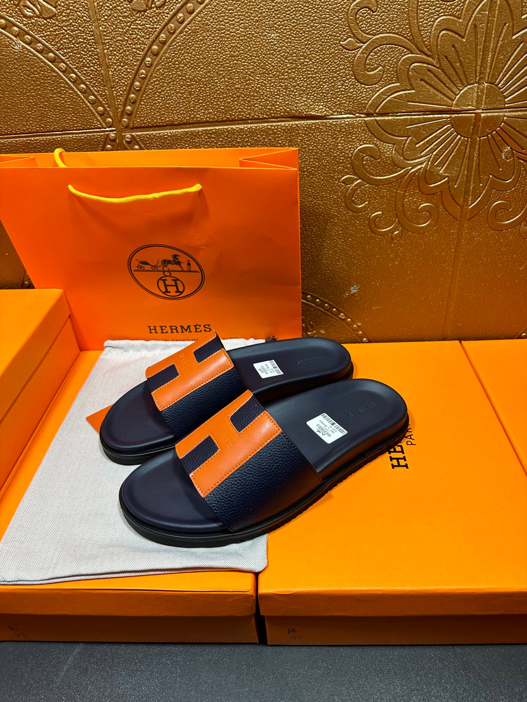Hermes slide sandals with dark navy upper and orange H panel detail on flat footbed