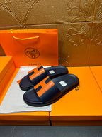 Hermes slide sandals with dark navy upper and orange H panel detail on flat footbed