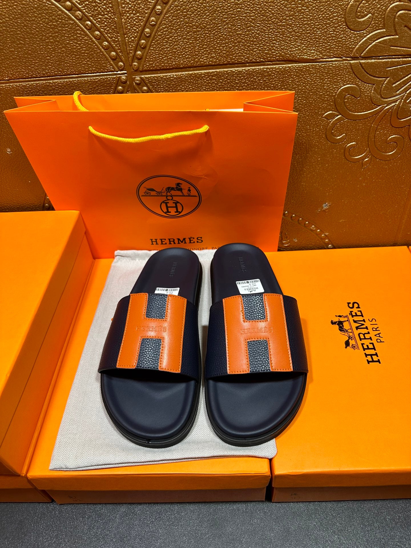Hermes slide sandals with dark navy straps, orange H detail, and cushioned footbed
