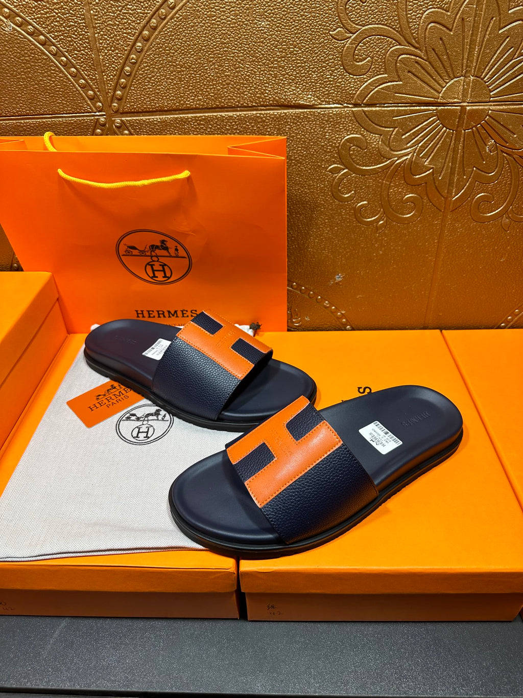 Hermes slide sandals, dark navy with orange H straps and smooth leather-like footbed