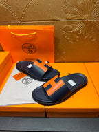 Hermes slide sandals, dark navy with orange H straps and smooth leather-like footbed