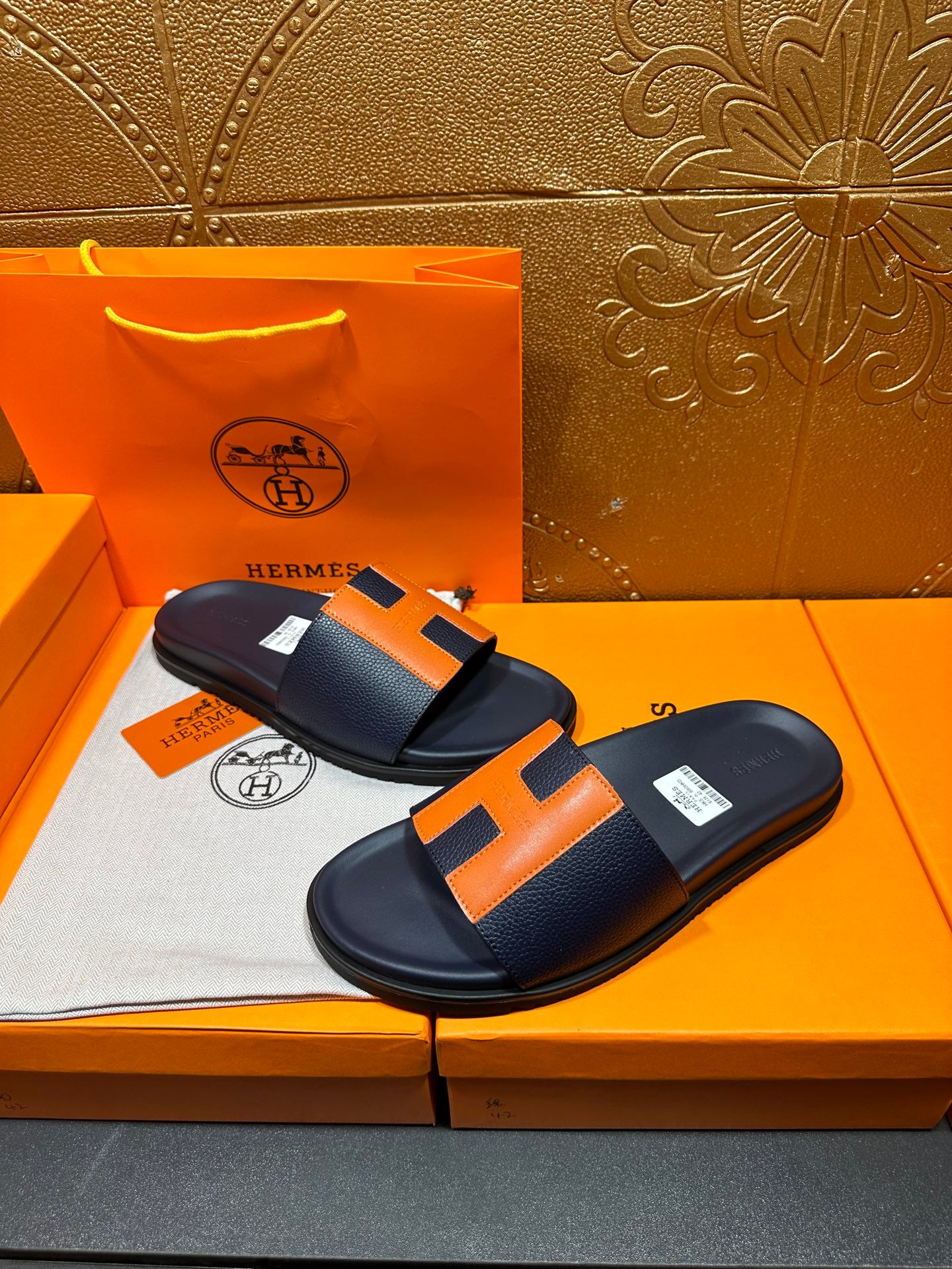 Hermes slide sandals, dark navy with orange H straps and smooth leather-like footbed