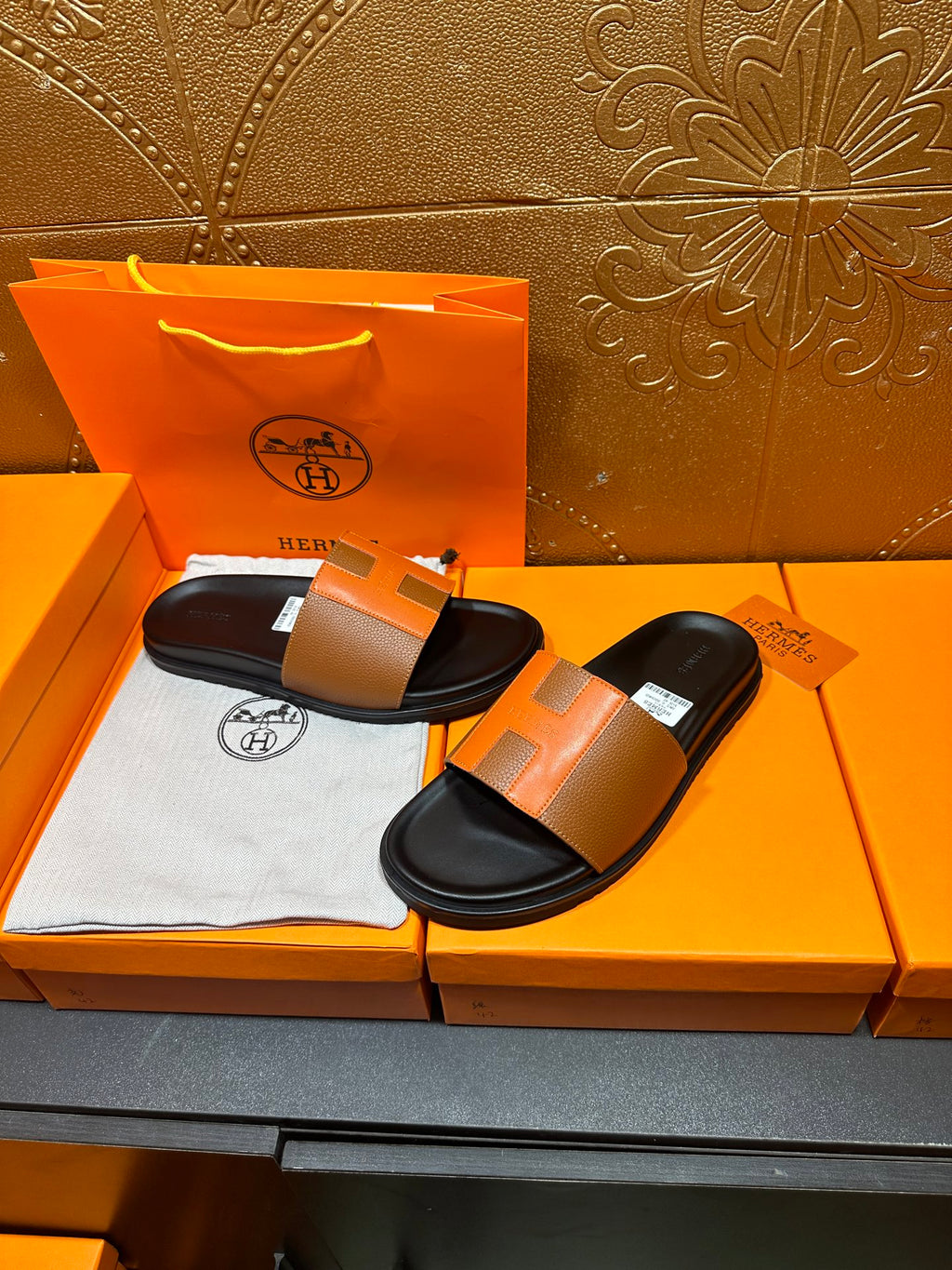 Tan leather slide sandals on display with black footbeds and wide strap
