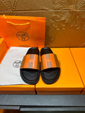 Tan-and-black leather slide sandals with wide strap and black footbed