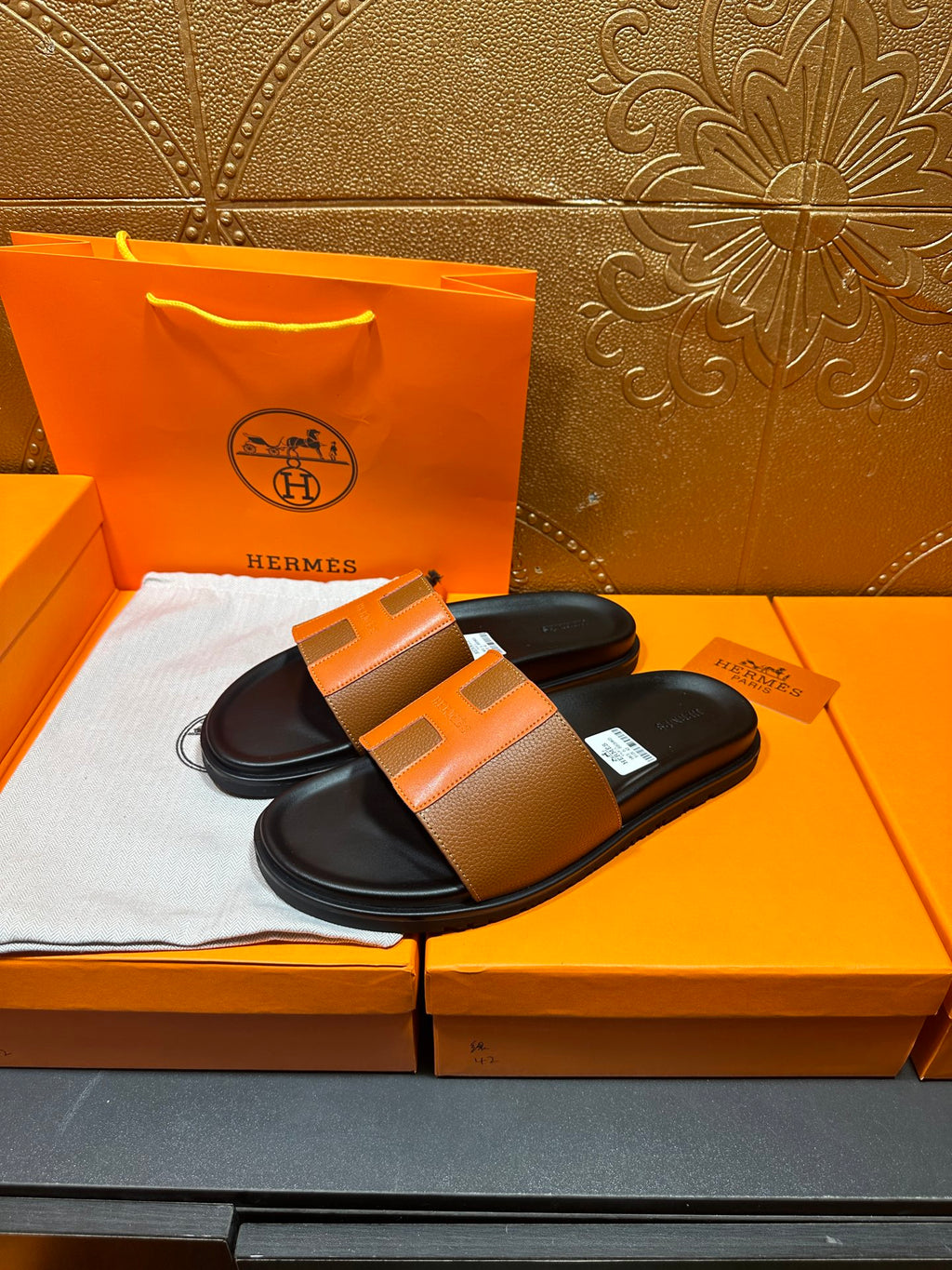 Tan leather slide sandals with black footbed and wide orange-toned strap