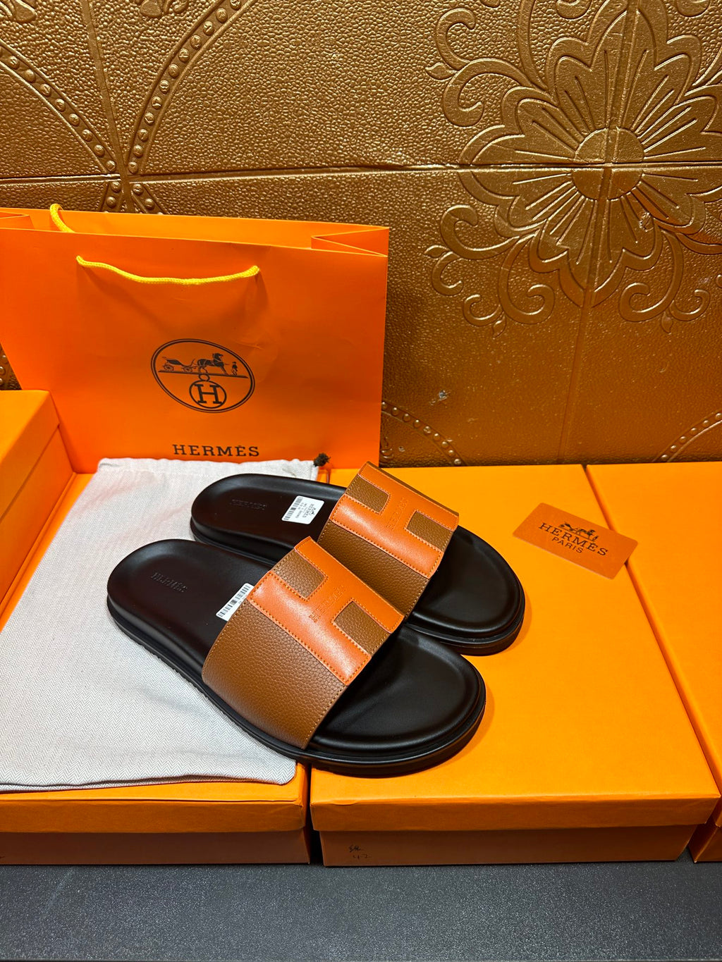 Pair of tan leather slide sandals with black footbeds and wide strap
