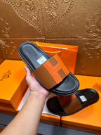 Tan leather slide sandals with black footbed and wide buckle-style strap