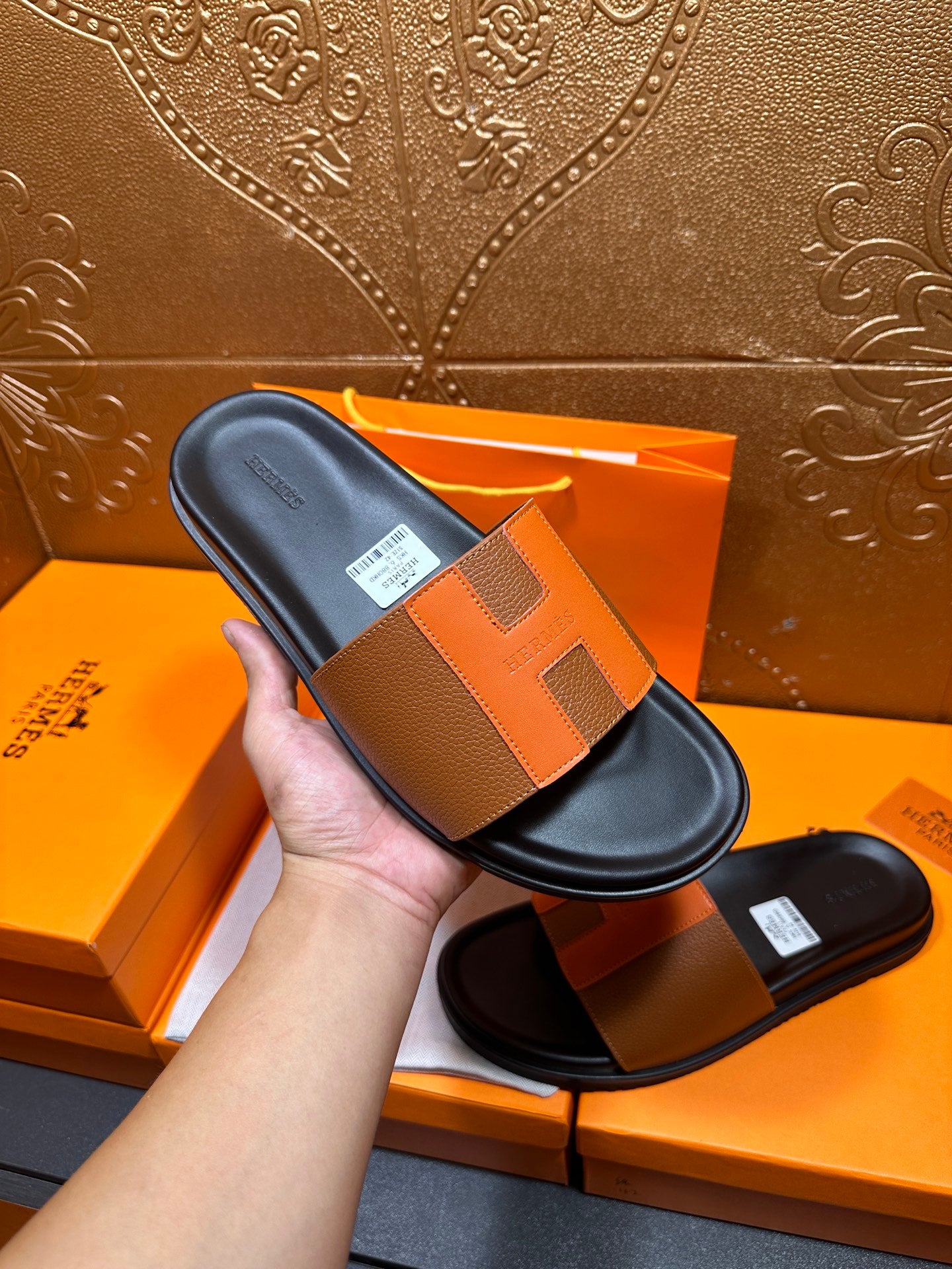 Tan leather slide sandals with black footbed and wide buckle-style strap