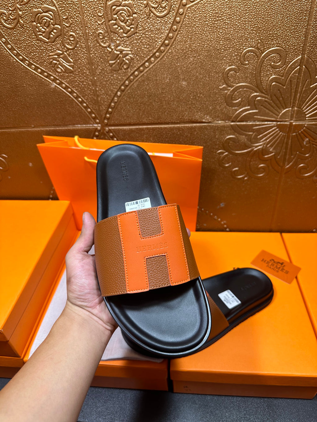 Tan leather slide sandal held upright over black footbed and wide strap