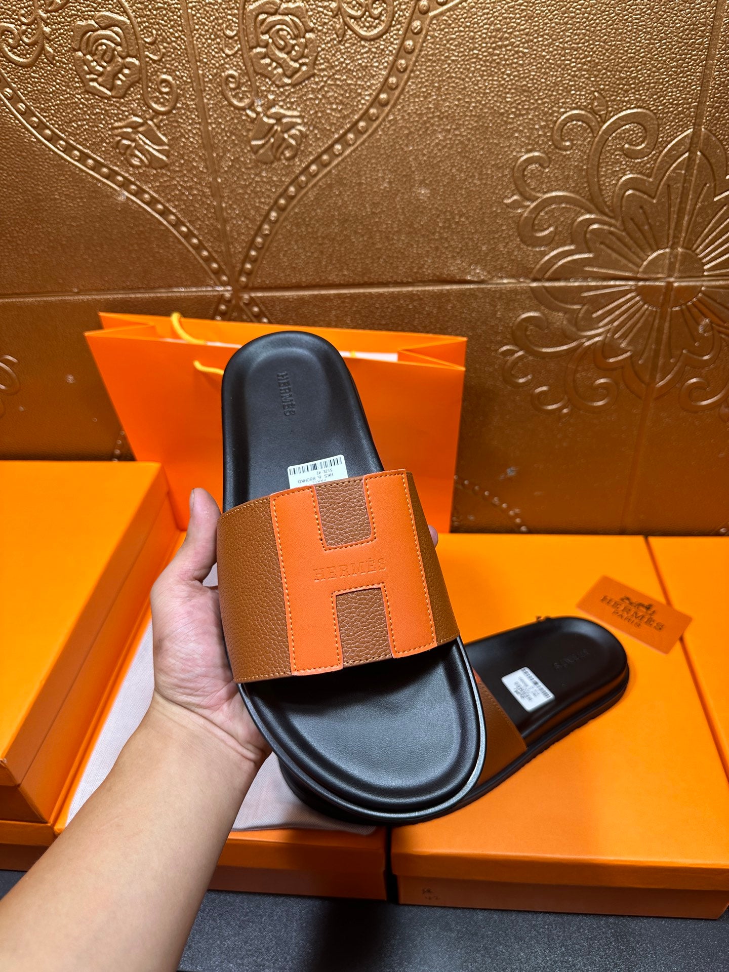 Tan leather slide sandal held upright over black footbed and wide strap