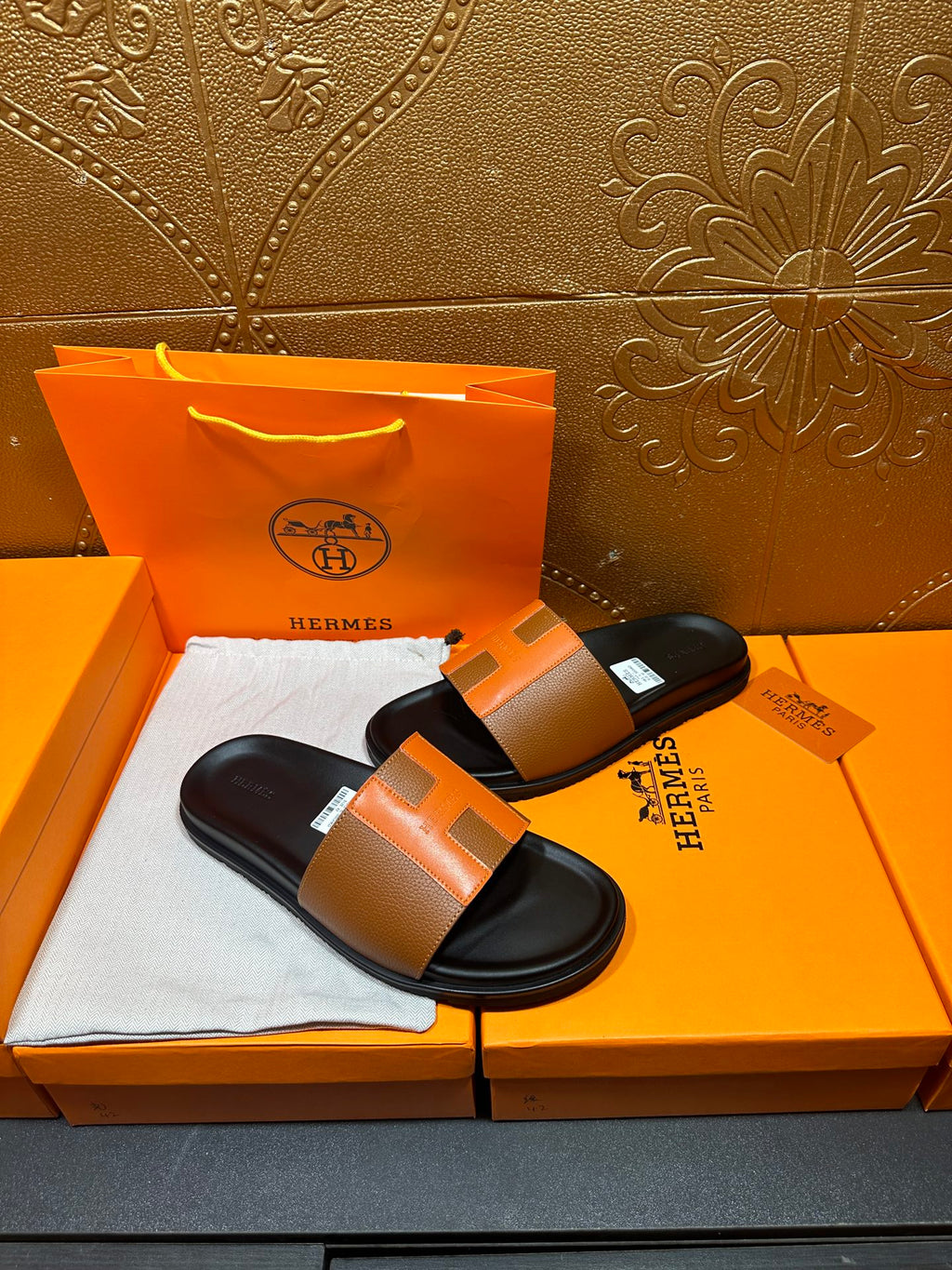 Tan leather slide sandals with black footbeds and wide strap, shown side-by-side