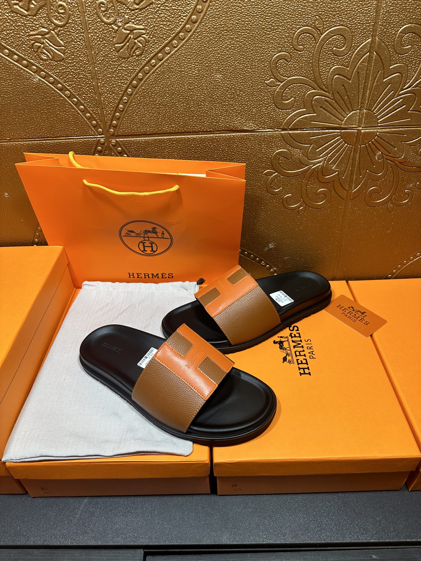 Tan leather slide sandals with black footbeds and wide strap, shown side-by-side