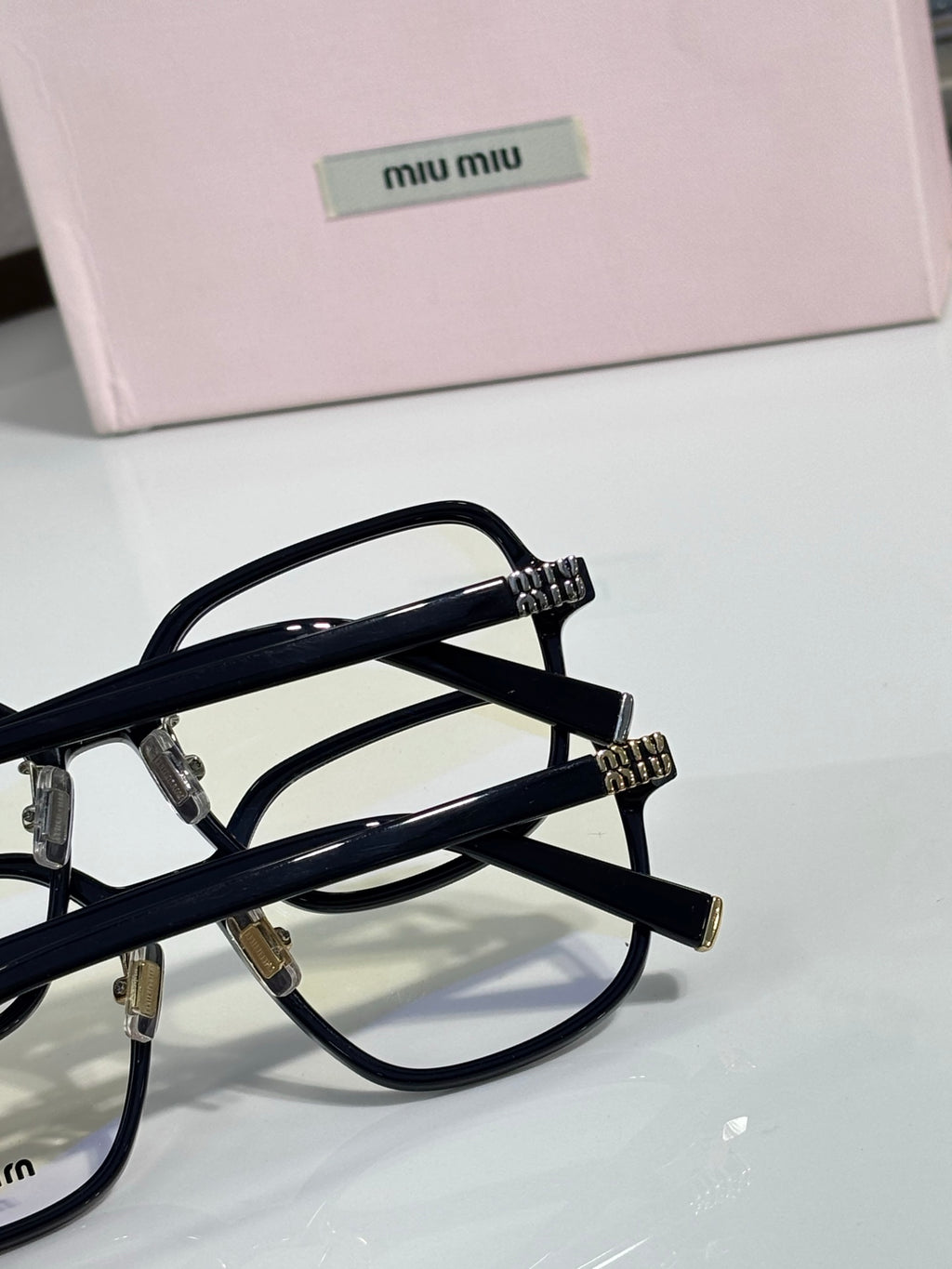 Close-up black eyeglass frame with clear lenses and MiuMiu logo on the temple