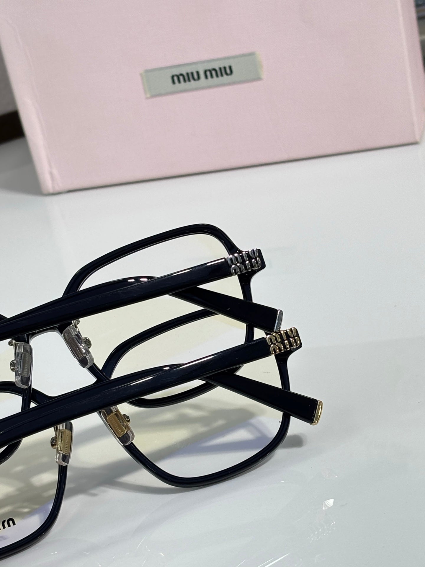 Close-up black eyeglass frame with clear lenses and MiuMiu logo on the temple