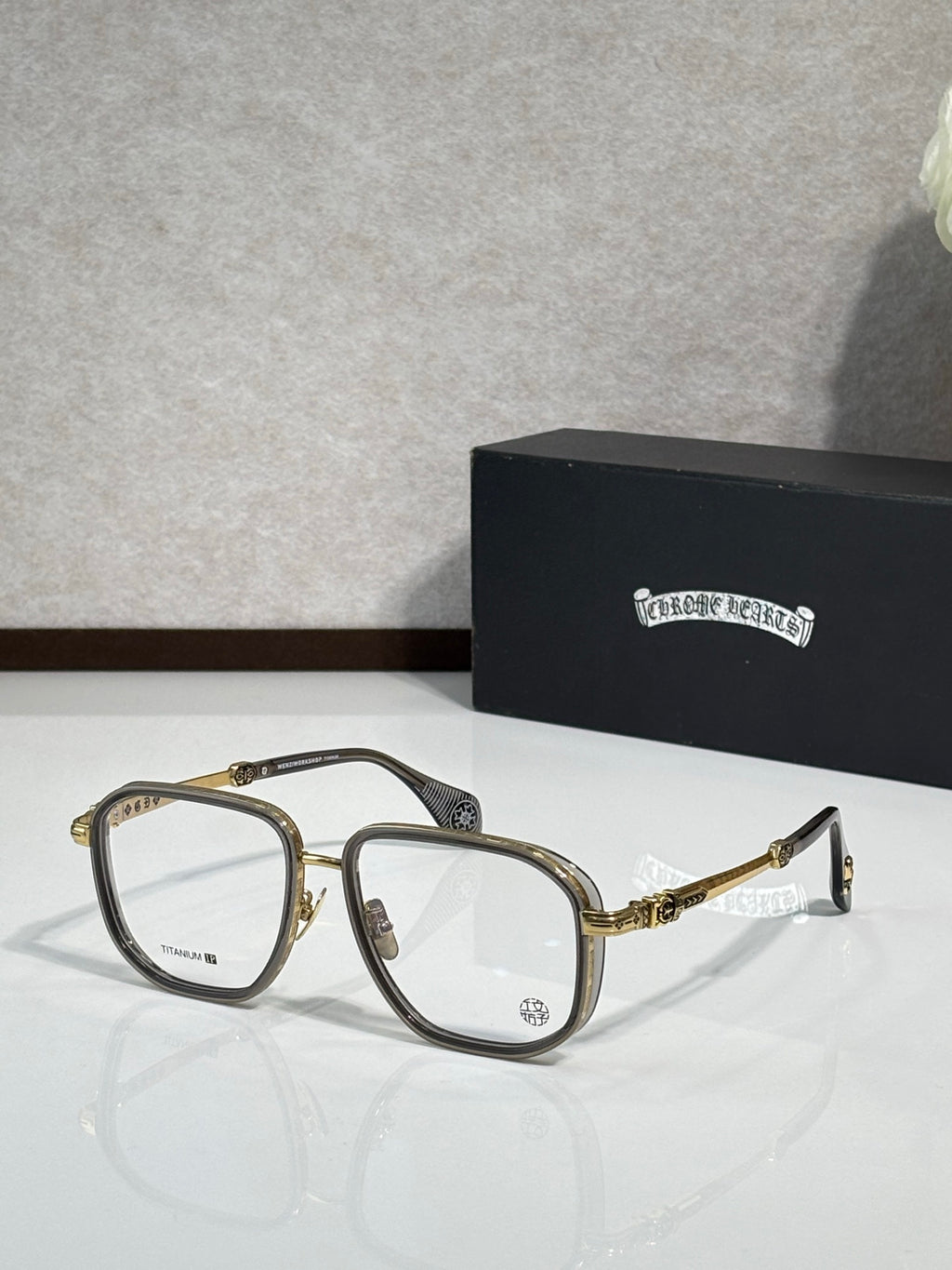 Gold-tone and black eyeglass frames with clear lenses and metal temple detailing.