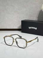 Gold-tone and black eyeglass frames with clear lenses and metal temple detailing.