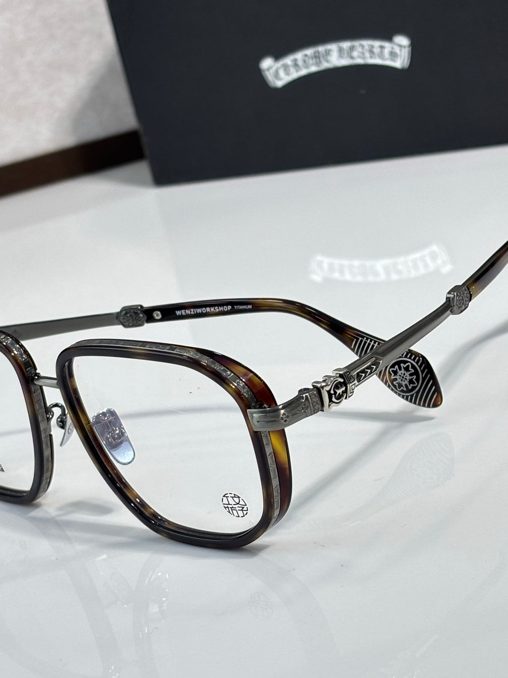 Tortoiseshell eyeglass frames with clear lenses and gold-tone carved metal accents.