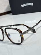 Tortoiseshell eyeglass frames with clear lenses and gold-tone carved metal accents.