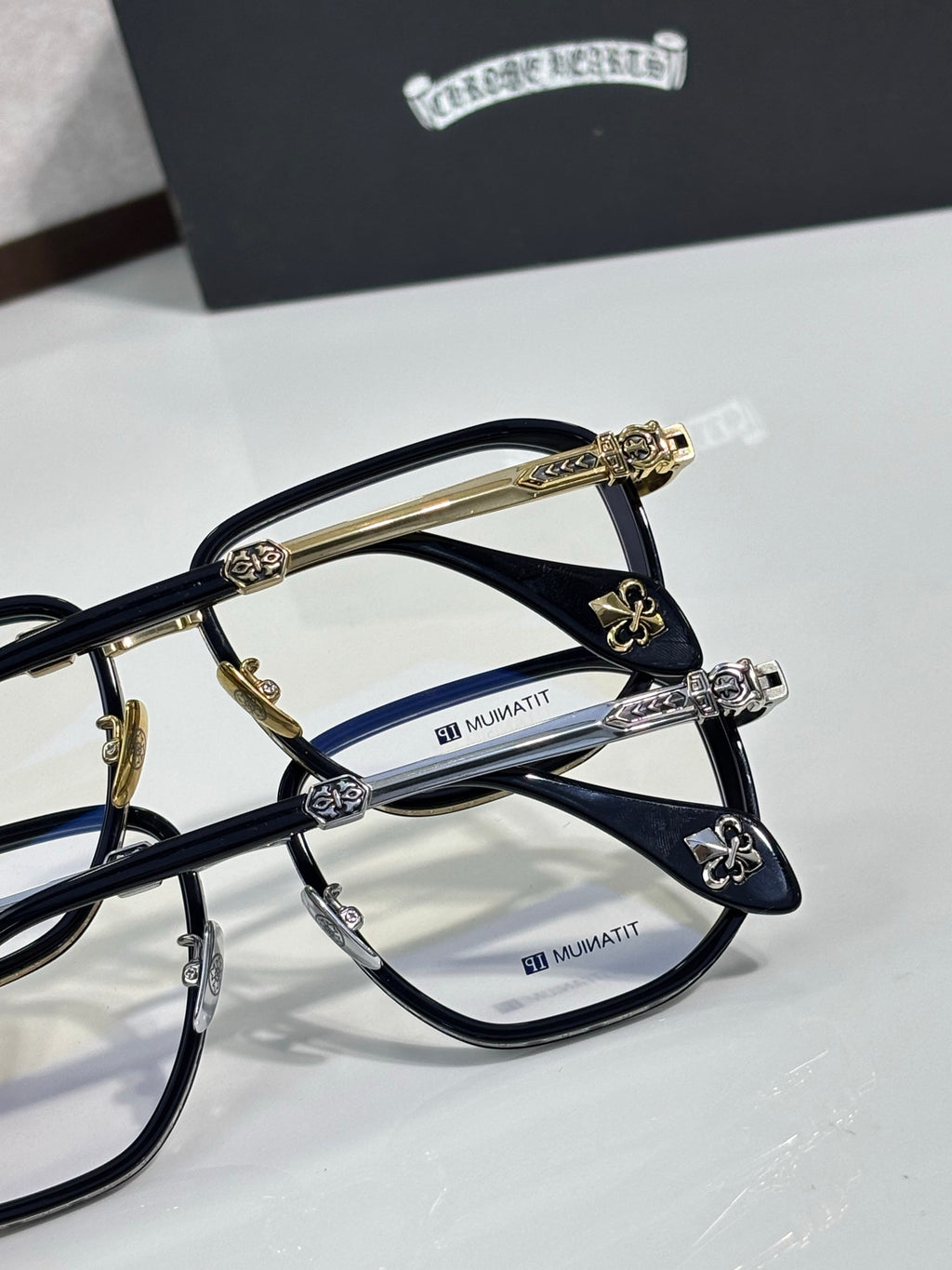 Dark navy eyeglass frames with clear lenses and gold-tone carved temple accents.