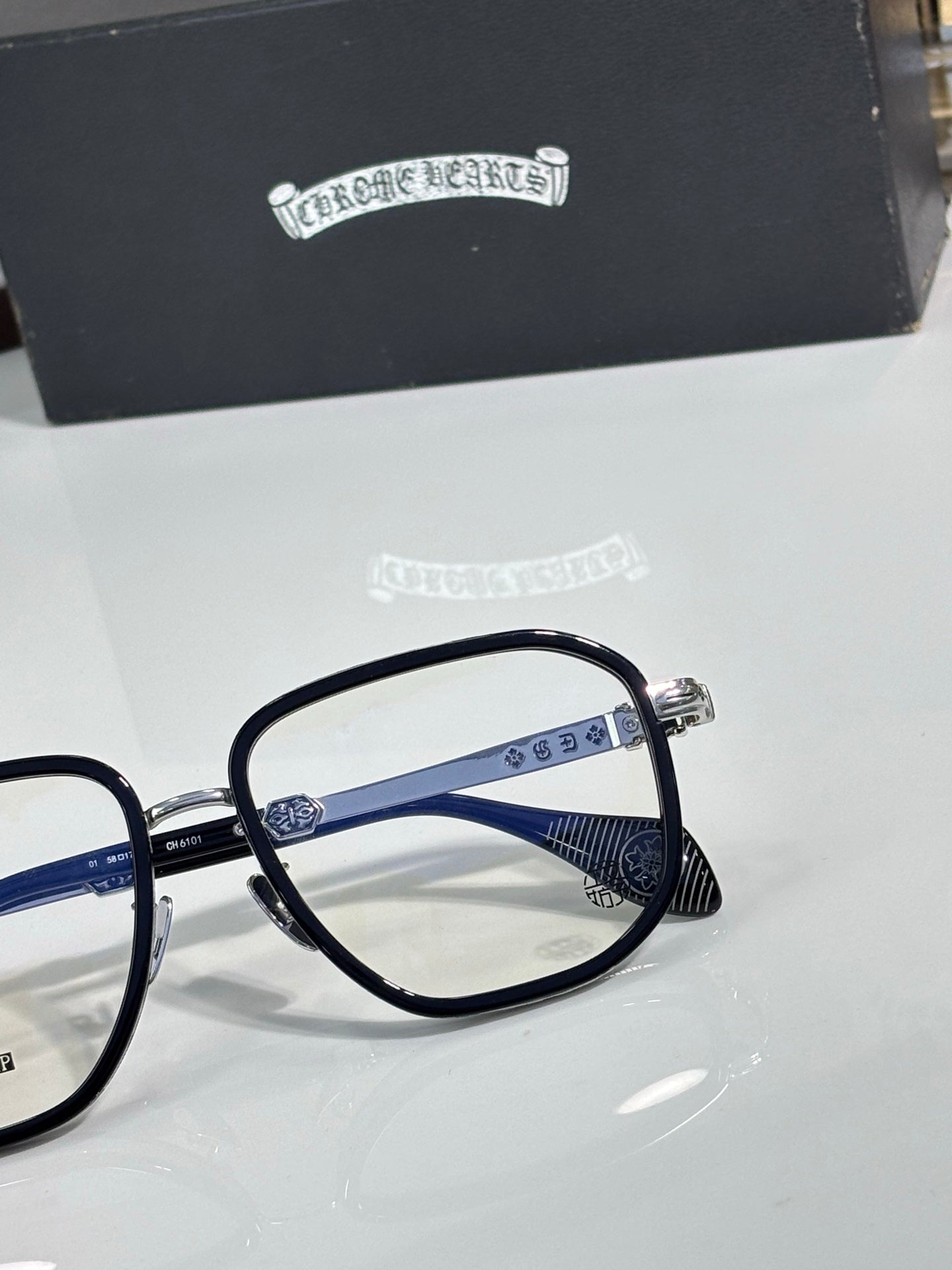 Close-up of eyeglass frames showing dark lenses and blue metal temple arm details.