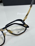 Gold-tone eyeglass frames with dark navy temples and clear lenses.