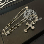 Silver-tone cross pendant necklace on black box with embossed logo
