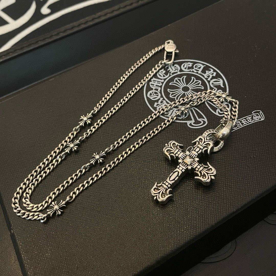 Silver-tone cross pendant necklace on black box with embossed logo