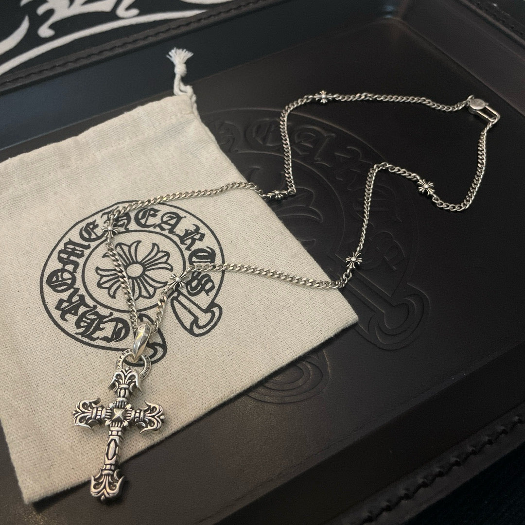 Silver-tone cross pendant necklace on black case with beige pouch and chain