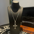 Silver-tone cross pendant necklace on black display bust with chain