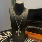 Silver-tone cross pendant necklace on black display bust with chain