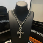 Silver-tone cross pendant necklace with detailed cross charm on black bust
