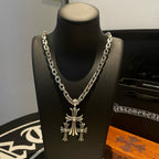 Silver chain necklace featuring a large cross pendant on display bust