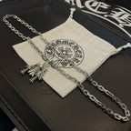 Silver cross pendant necklace draped over fabric pouch on black box