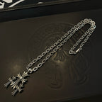 Silver cross pendant necklace laid on black box, chain visible