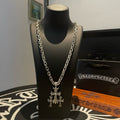 Silver chain necklace with cross pendant on black display bust