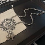 Silver cross pendant necklace on fabric pouch with chain links visible